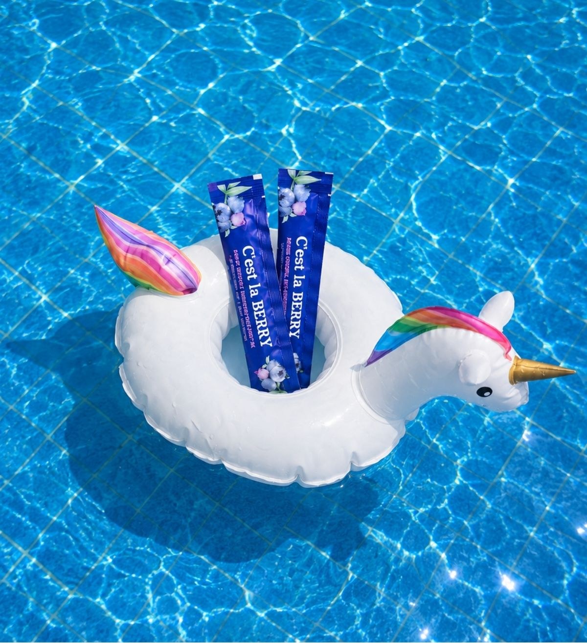 Blue skincare sachets in a unicorn pool float on sparkling water