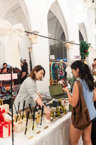 A shopper trying a fragrance at a perfume stall