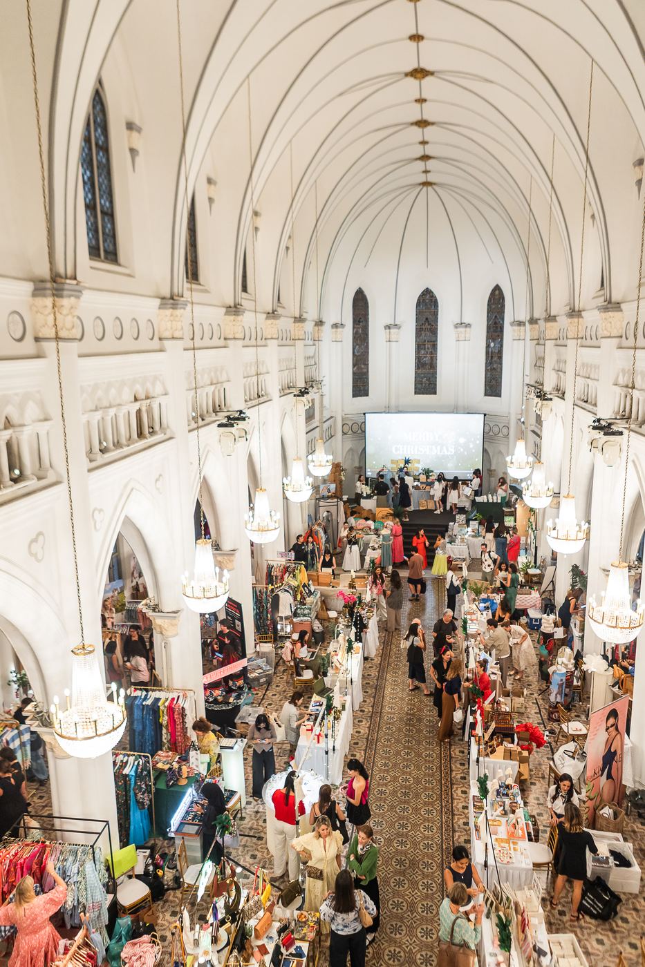 Aerial view of the market filling CHIJMES Hall, with a Merry Christmas screen at the far end