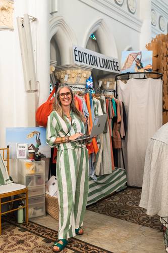 A brand founder holding a laptop beside her striped linen collection