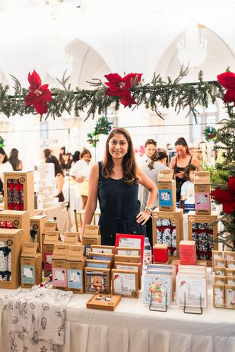 A maker smiling behind her table of Christmas crackers and cards
