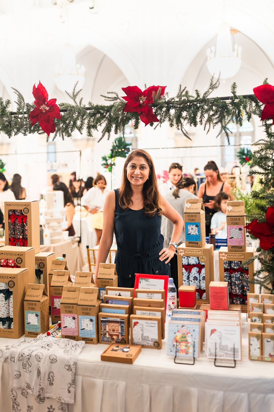 A maker smiling behind her table of Christmas crackers and cards